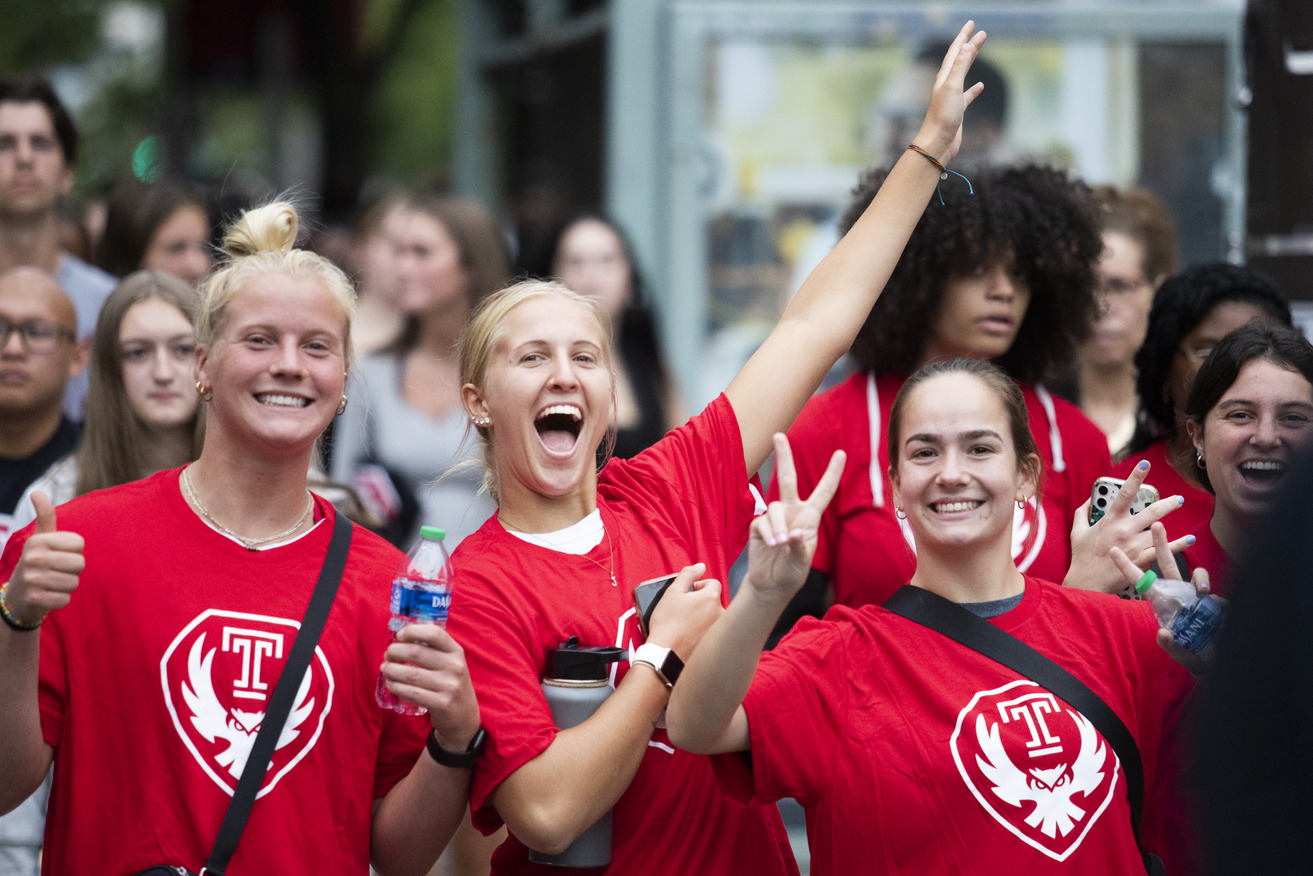 Students smiling and giving peace signs in Temple shirts
