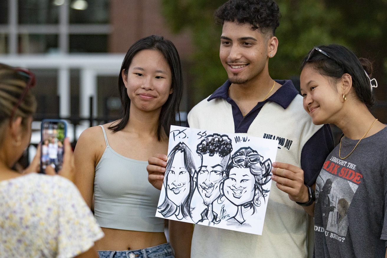 Students holding up caricature drawing of themselves